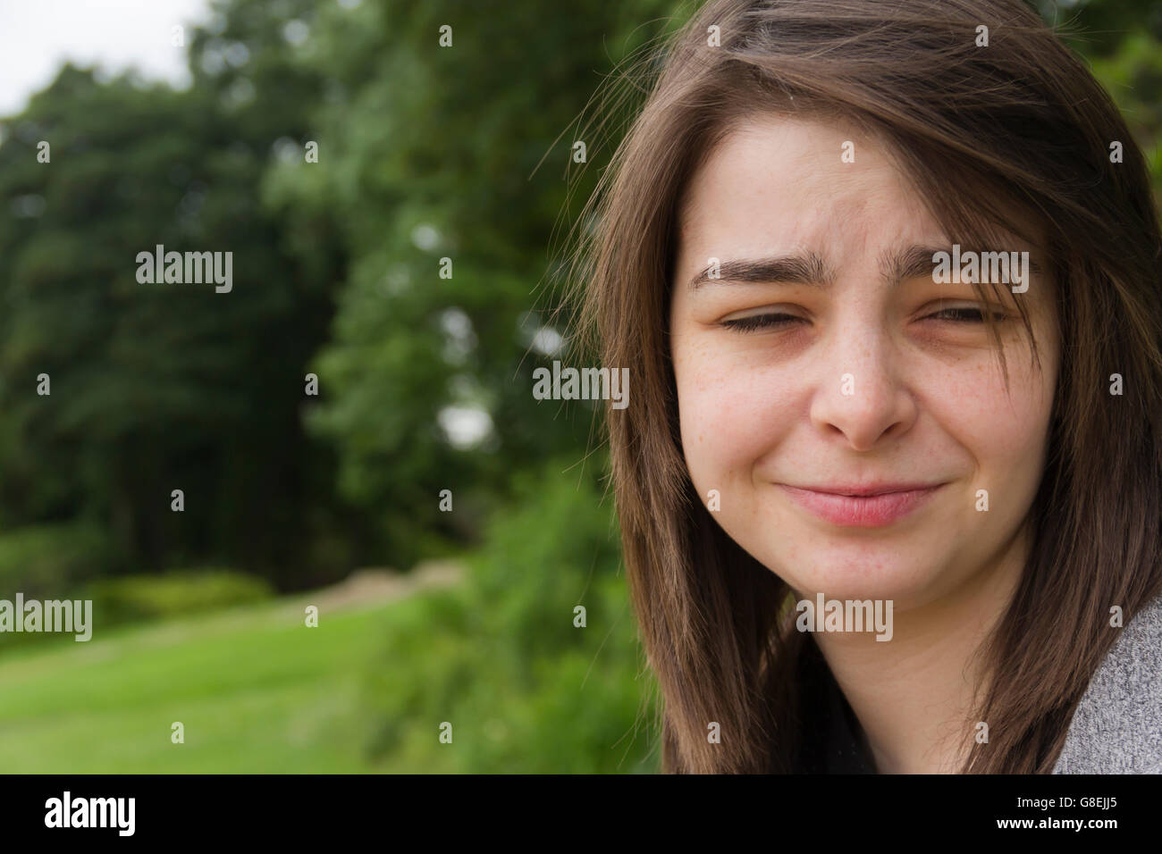 Junge Frau, Erwachsene oder späten Teens, sitzen im Park mit einem Ungläubigen oder Zweifeln Ausdruck auf ihrem Gesicht. Stockfoto