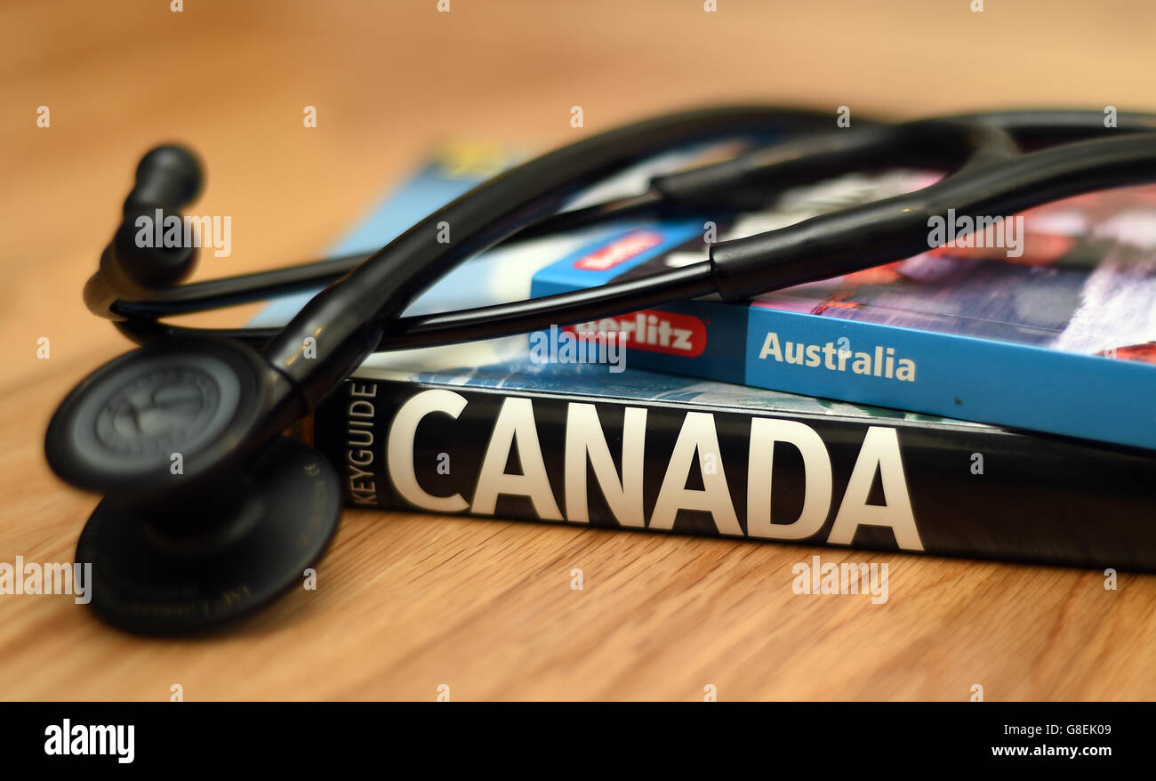 Ein Arztstethoskop liegt auf Reiseführern nach Australien und Kanada Stockfoto