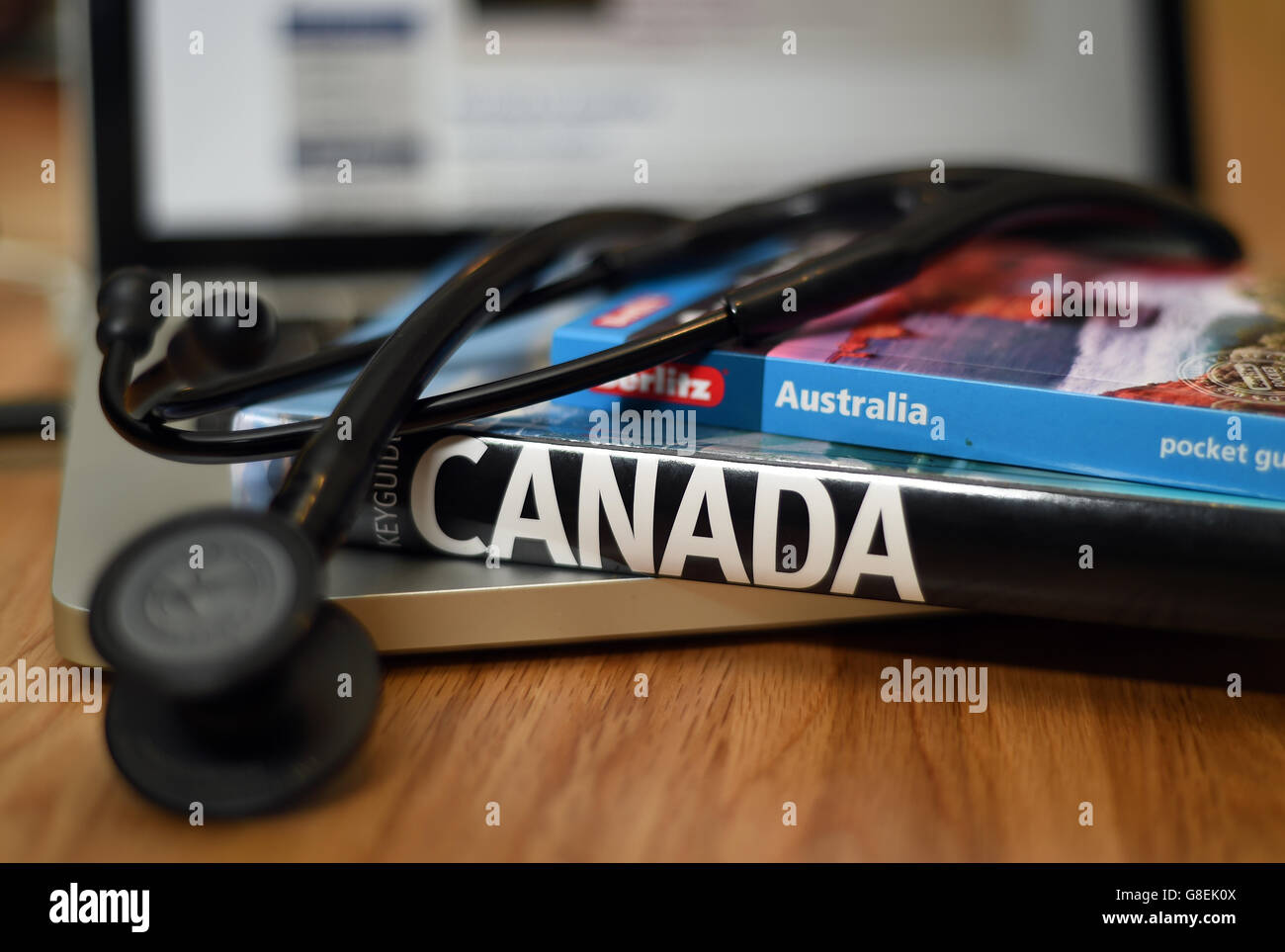 Ein Arztstethoskop liegt auf Reiseführern nach Australien und Kanada Stockfoto