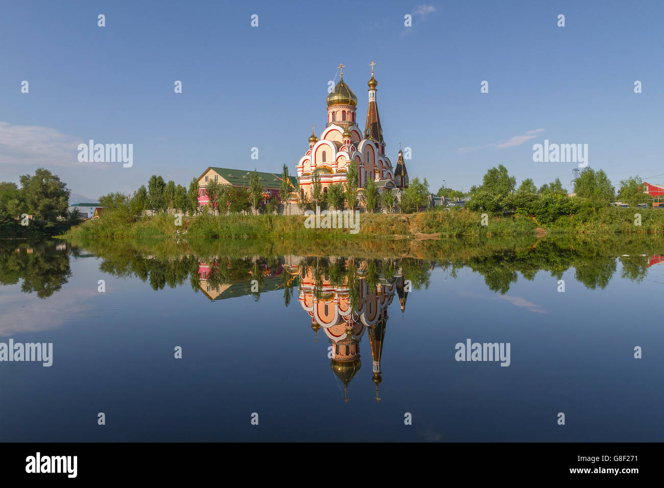 Russisch-orthodoxe Kirche in Almaty, Kasachstan, auch bekannt als Kirche der Erhöhung des Heiligen Kreuzes und dessen Spiegelbild im Wasser. Stockfoto