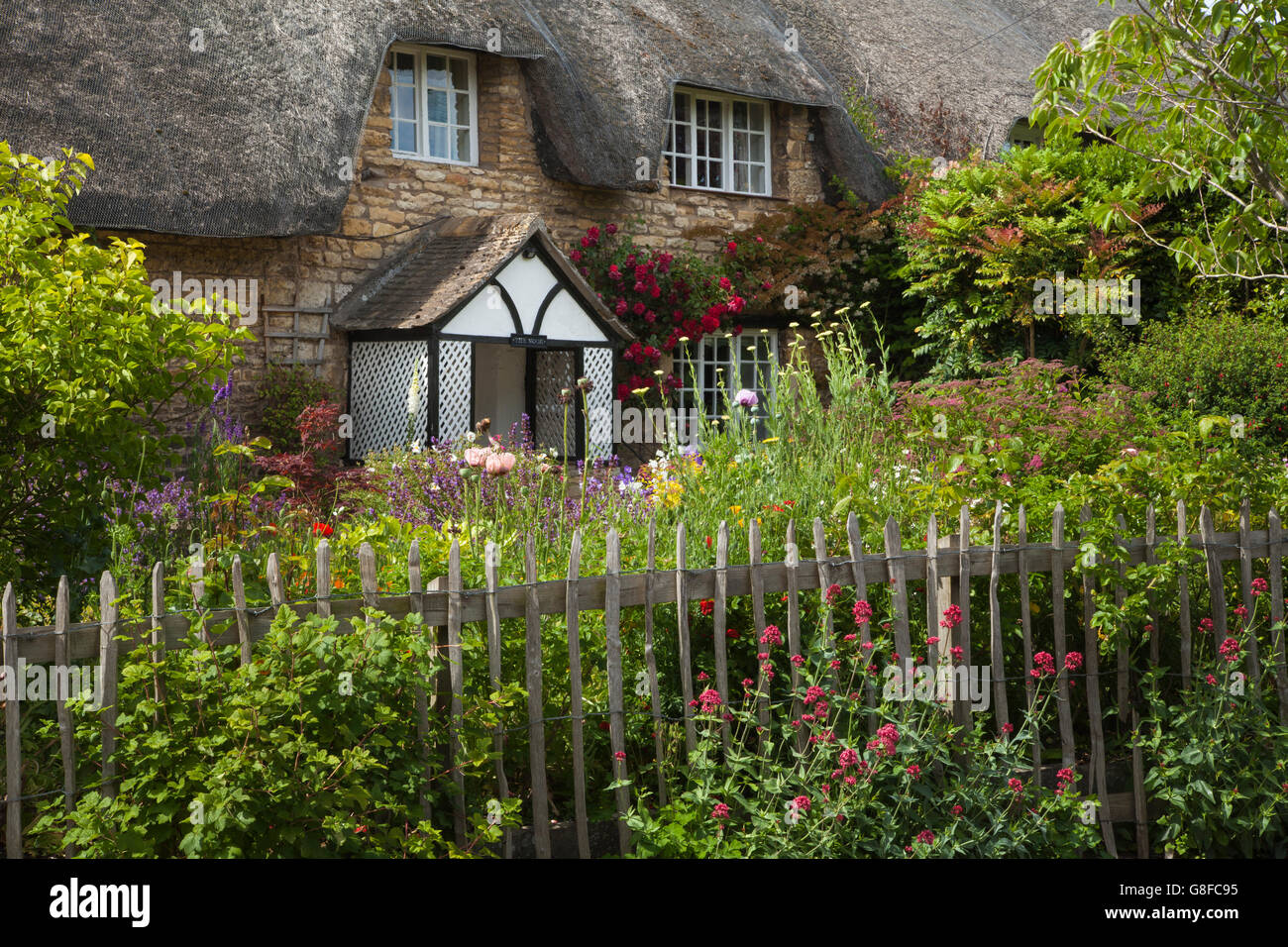 Ein traditionelles Stein Reetdachhaus mit lattenzaun und ein Garten
