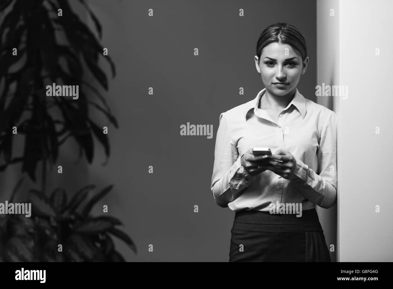 Porträt des jungen glücklich erfolgreiche Geschäftsfrau In Anzug überprüft ihr Handy im Büro - Kauffrau Online arbeiten Stockfoto
