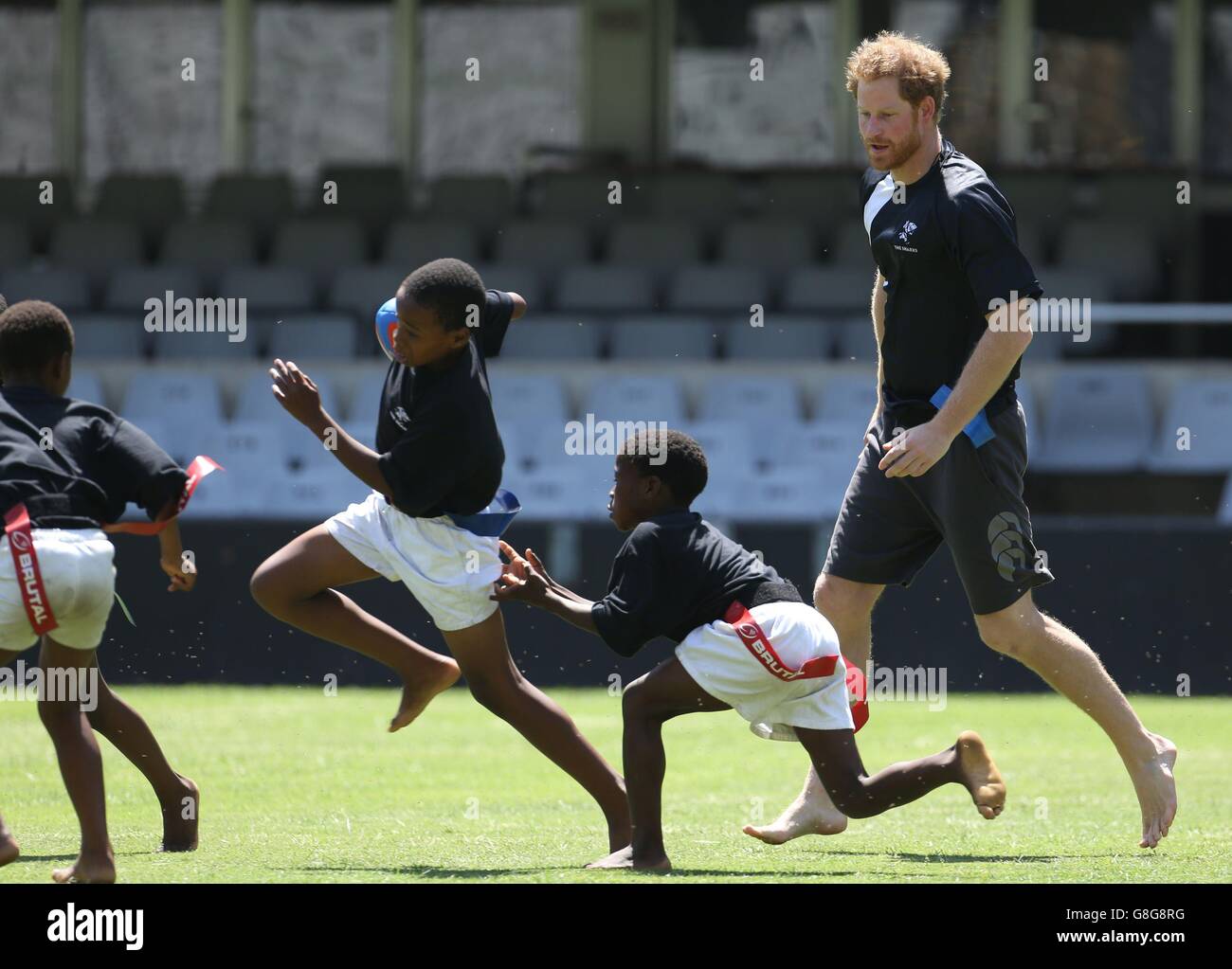 Prince Harry spielt Tag Rugby mit Kindern im Kings Park Stadium, während er sich mit Mitgliedern des Sharks Rugby Teams auf dem Spielfeld in Durban in einem Training und Skills Sessions mit Trainern und jungen Spielern im Rahmen seines Besuchs in Südafrika trifft. Stockfoto