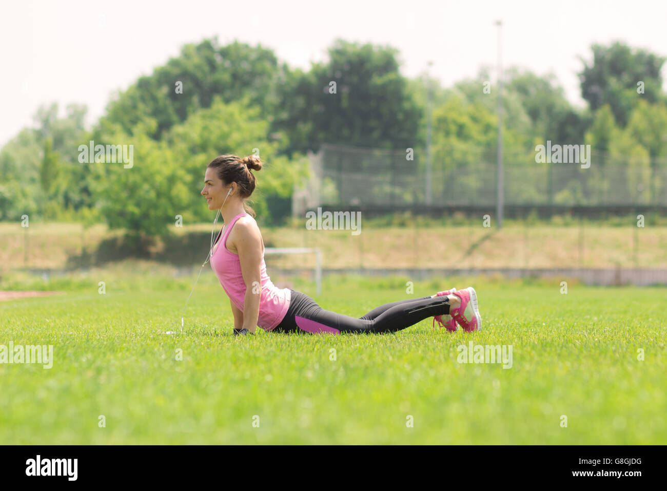 Sportliche junge Mädchen Cobra Stretch Rasen Magen mit Blick auf Boden Stockfoto