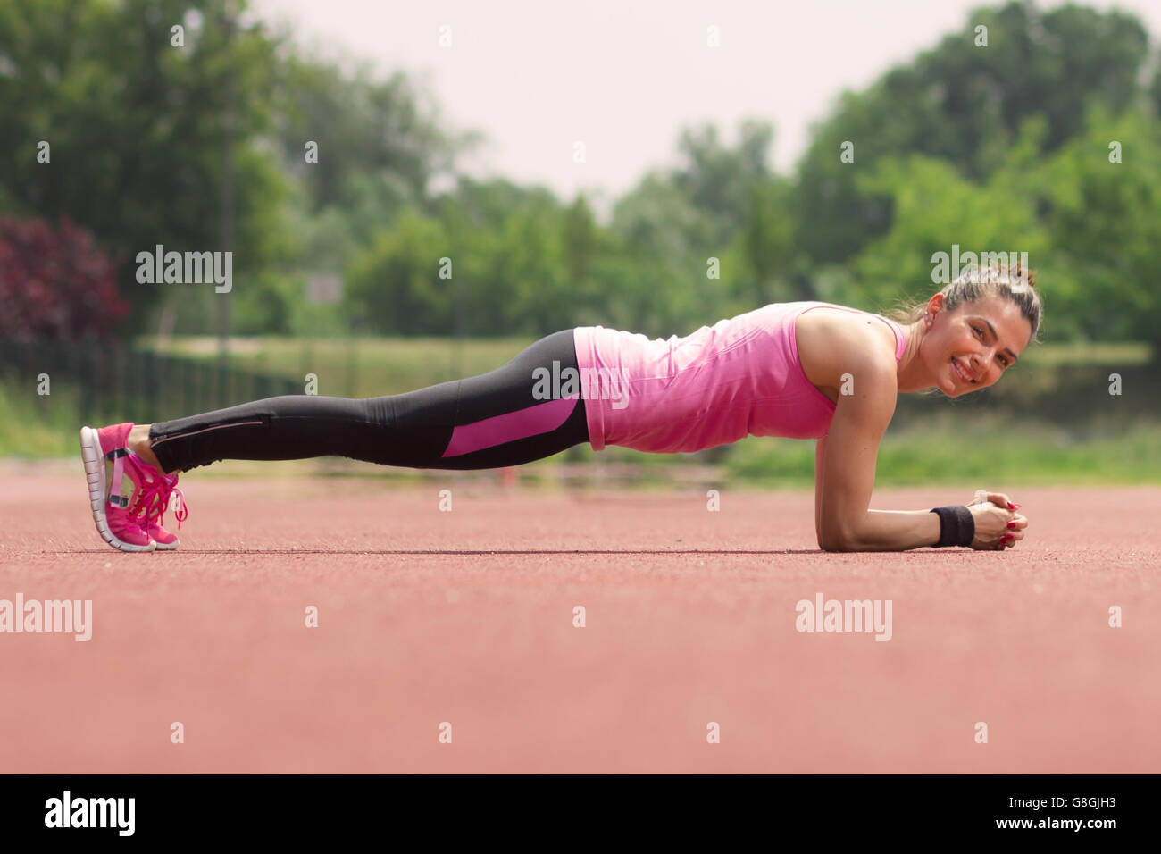 Seitenansicht, glücklich lächelnd, Mädchen Plank im freien Stockfoto