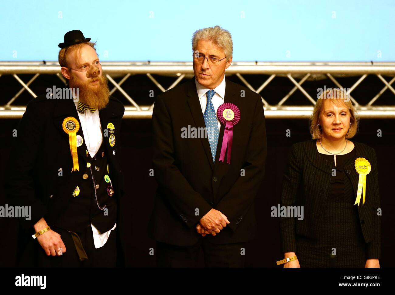 Der UKIP-Kandidat John Bickley (Mitte) hört sich die Erklärung mit Sir Oink Alot, Kandidat der offiziellen Monster Raving Party (links) und der Lib-dem-Kandidatin Jane Brophy (rechts) bei der Nachwahlzählung der Oldham West- und Royton-Wahlkreise im Civic Center in Oldham an. Stockfoto