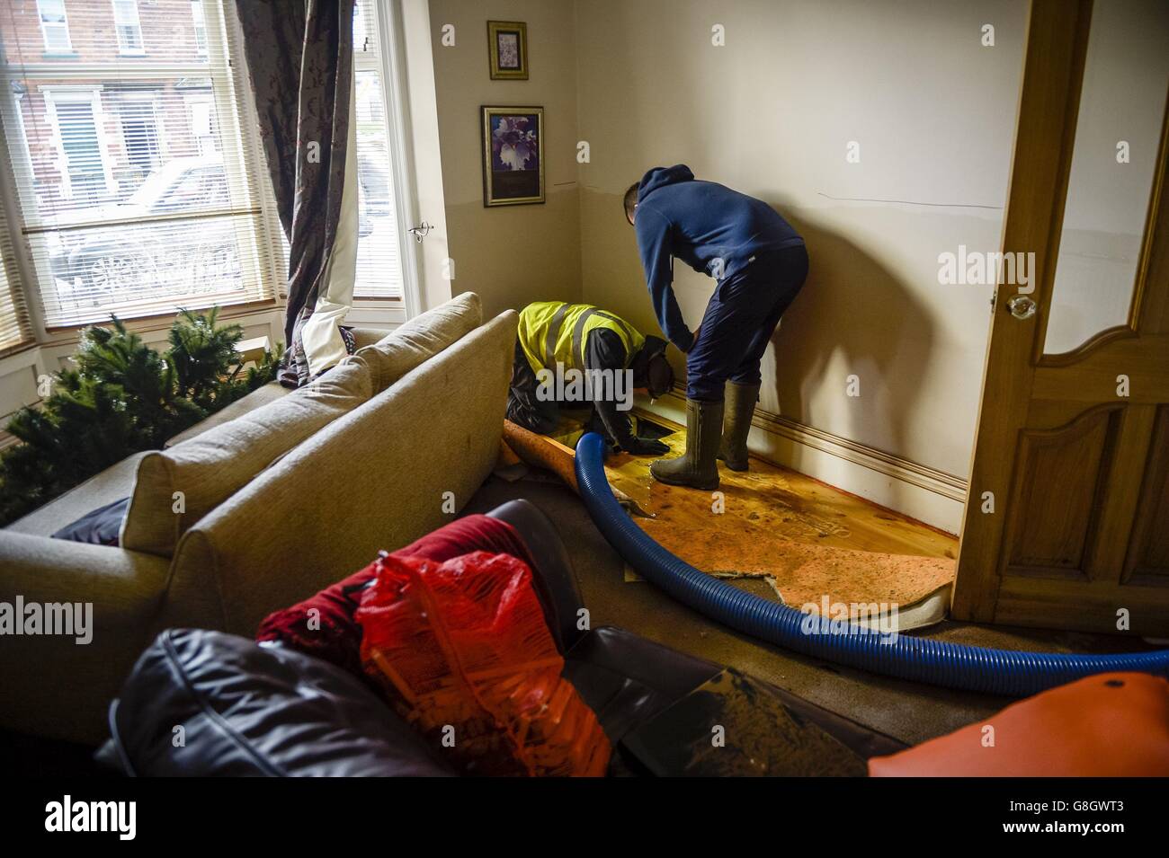 Die Arbeiter Pumpen Wasser aus den Dielen eines Hauses an der Warwick Road, während die Säuberung nach den Überschwemmungen in Carlisle beginnt. Stockfoto