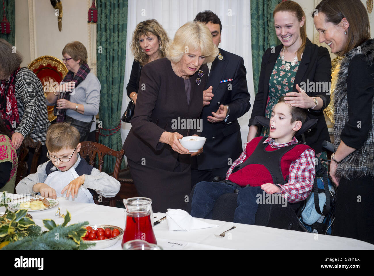 Die Herzogin von Cornwall hilft Thomas Melville-Ross (rechts sitzend) bei einer Veranstaltung, um den Weihnachtsbaum des Clarence House mit Kindern zu schmücken, die von Helen & Douglas House und dem London Taxi Drivers' Fund for Underprivileged Children unterstützt werden. Stockfoto