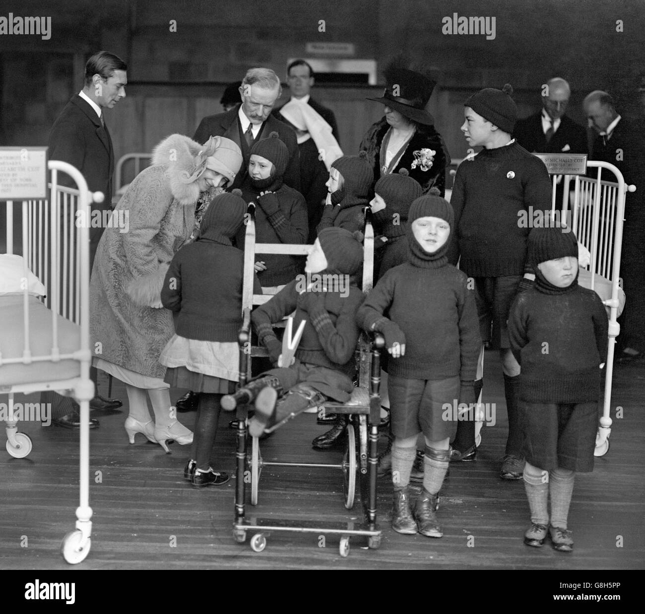 Der Herzog und die Herzogin von York unterhalten sich mit Patienten neben dem Kinderbett der Prinzessin Elizabeth während der Eröffnung des Crippled Children's Hospital in Exeter. Stockfoto