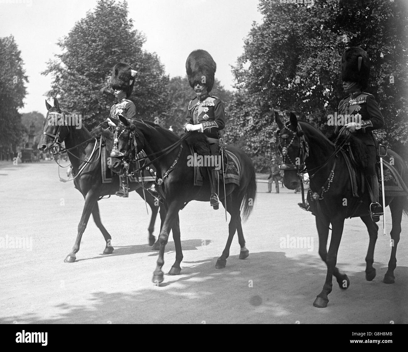König George V (Mitte) präsentiert den Wachen bei der Parade der Pferdewächter im Trooping the Color Farben. Stockfoto
