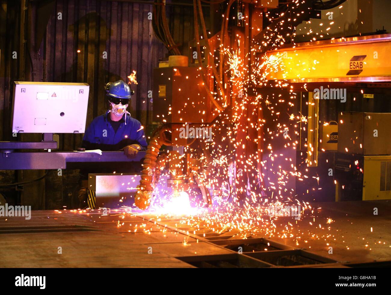 Ein Brenner verwendet einen Plasmaschneider, um Stahlplatten an Watson Towers in Coatbridge zu schneiden, um in die spezifischen Komponenten zu schneiden, die das Ende des Fachwerks auf der Forth Road Bridge fixieren. Stockfoto