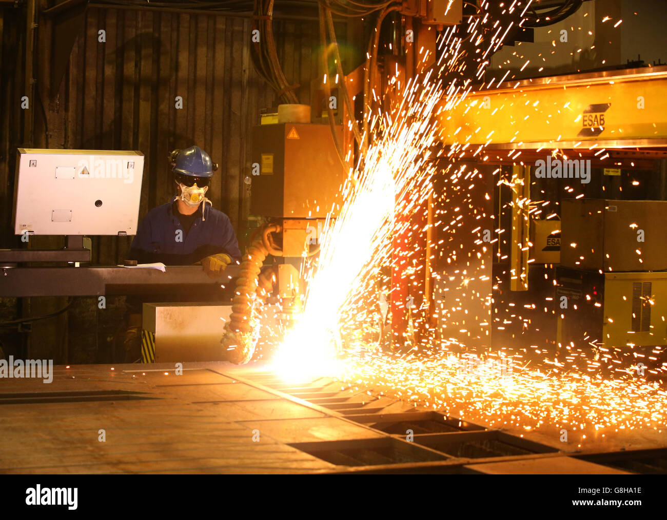 Ein Brenner verwendet einen Plasmaschneider, um Stahlplatten an Watson Towers in Coatbridge zu schneiden, um in die spezifischen Komponenten zu schneiden, die das Ende des Fachwerks auf der Forth Road Bridge fixieren. Stockfoto