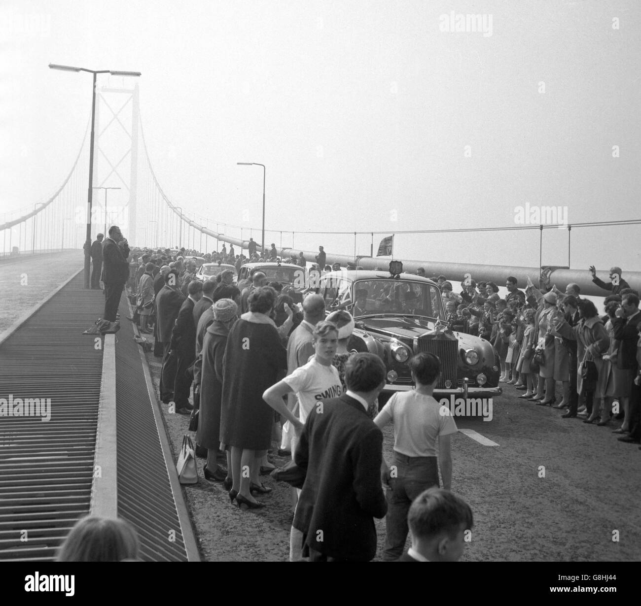 Das Auto der Königin fährt durch jubelnde Menschenmengen, während sie nach der Eröffnungszeremonie über die Forth Road Bridge fährt. Die Struktur ist die längste einspannige Hängebrücke in Europa und die viertgrößte der Welt. Stockfoto