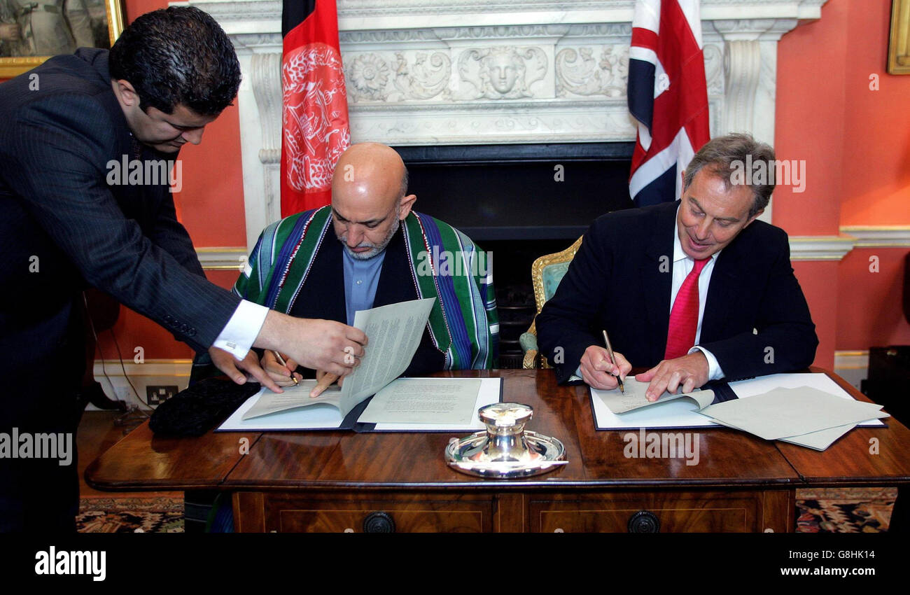 Der britische Premierminister Tony Blair und der Präsident der Islamischen Republik Afghanistan, Hamid Karzai (Mitte), unterzeichnen ein Kooperationsabkommen über 10 Jahre. Stockfoto