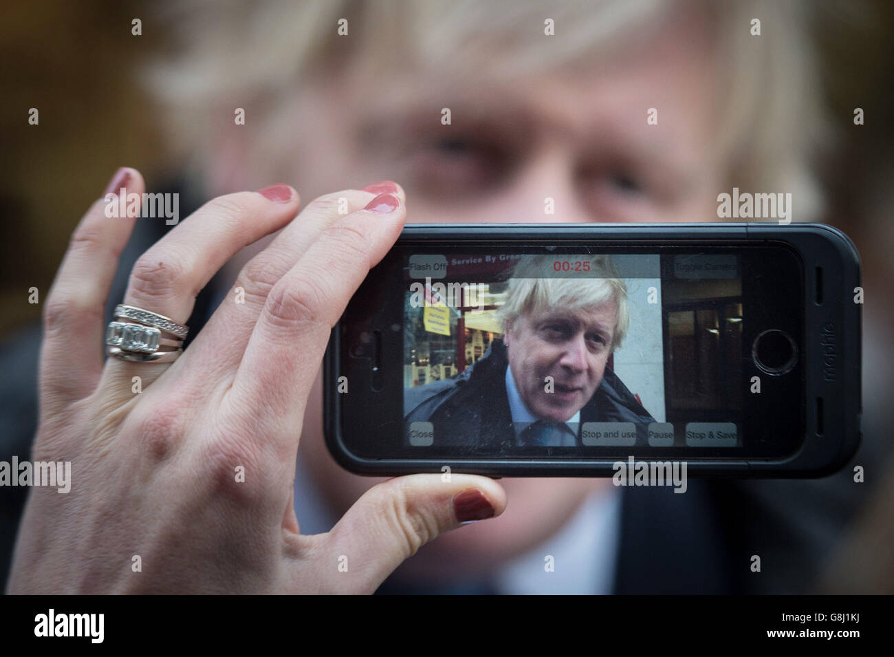Der Bürgermeister von London, Boris Johnson, wird von der BBC auf einem Mobiltelefon interviewt, nachdem er versucht hatte, Schlüssel zu schneiden und Schuhe in Timpson in der City of London zu flicken, wo er den Ex-Straftäter traf, Russell Zecanovsky, der von Timpson als Teil ihrer Politik beschäftigt wurde, Ex-Straftäter zu rekrutieren. Stockfoto