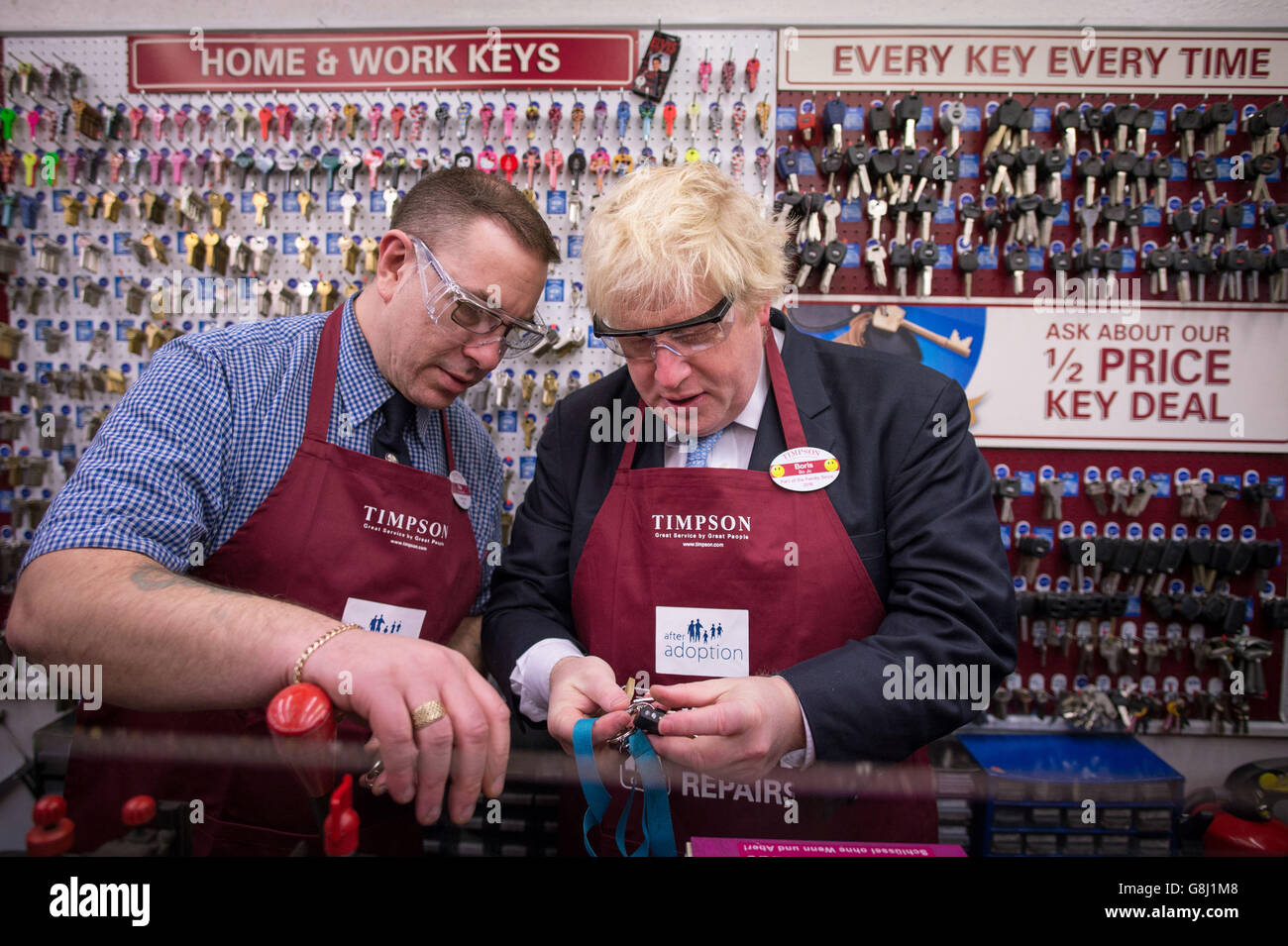 Der Bürgermeister von London, Boris Johnson, versucht sich bei Timpson in der City of London, Schlüssel zu schneiden und Schuhe auszubessern, wo er den Ex-Straftäter Russell Zecanovsky (links) traf, der von Timpson als Teil ihrer Politik zur Rekrutierung von Ex-Straftätern angestellt wurde. Stockfoto