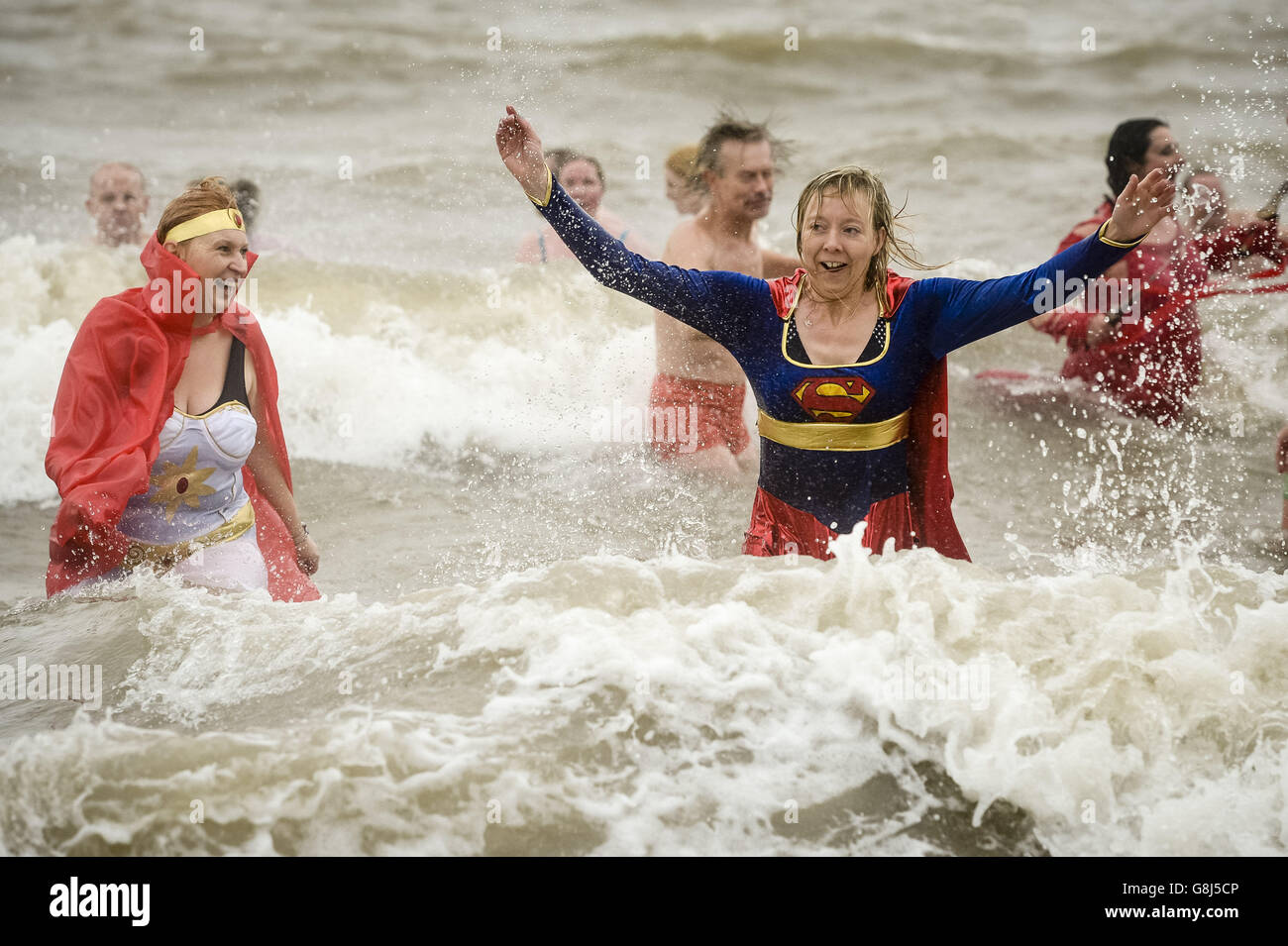 Auf Barry Island, in der Nähe von Cardiff in Wales, planschen Menschen in ausgefallenen Kleidern im Meer, wo das jährliche Neujahrsschwimmen stattfindet. Stockfoto