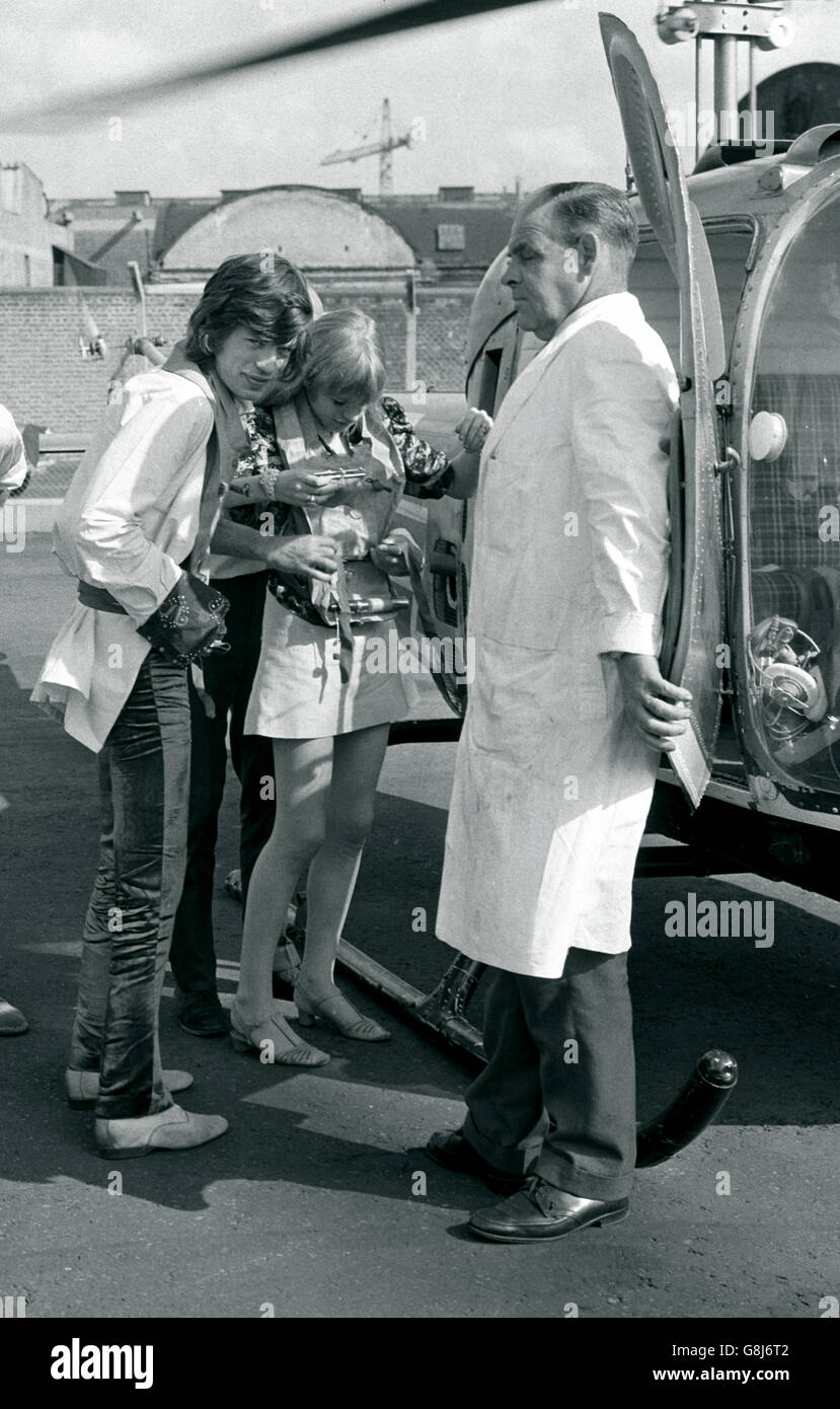 Mick Jagger, (links) von den Rolling Stones und seine Freundin, Popstar, Schauspielerin Marianne Faithfull, lassen ihre Rettungswesten aufstecken, bevor sie am Battersea Heliport in einen Hubschrauber steigen. Stockfoto
