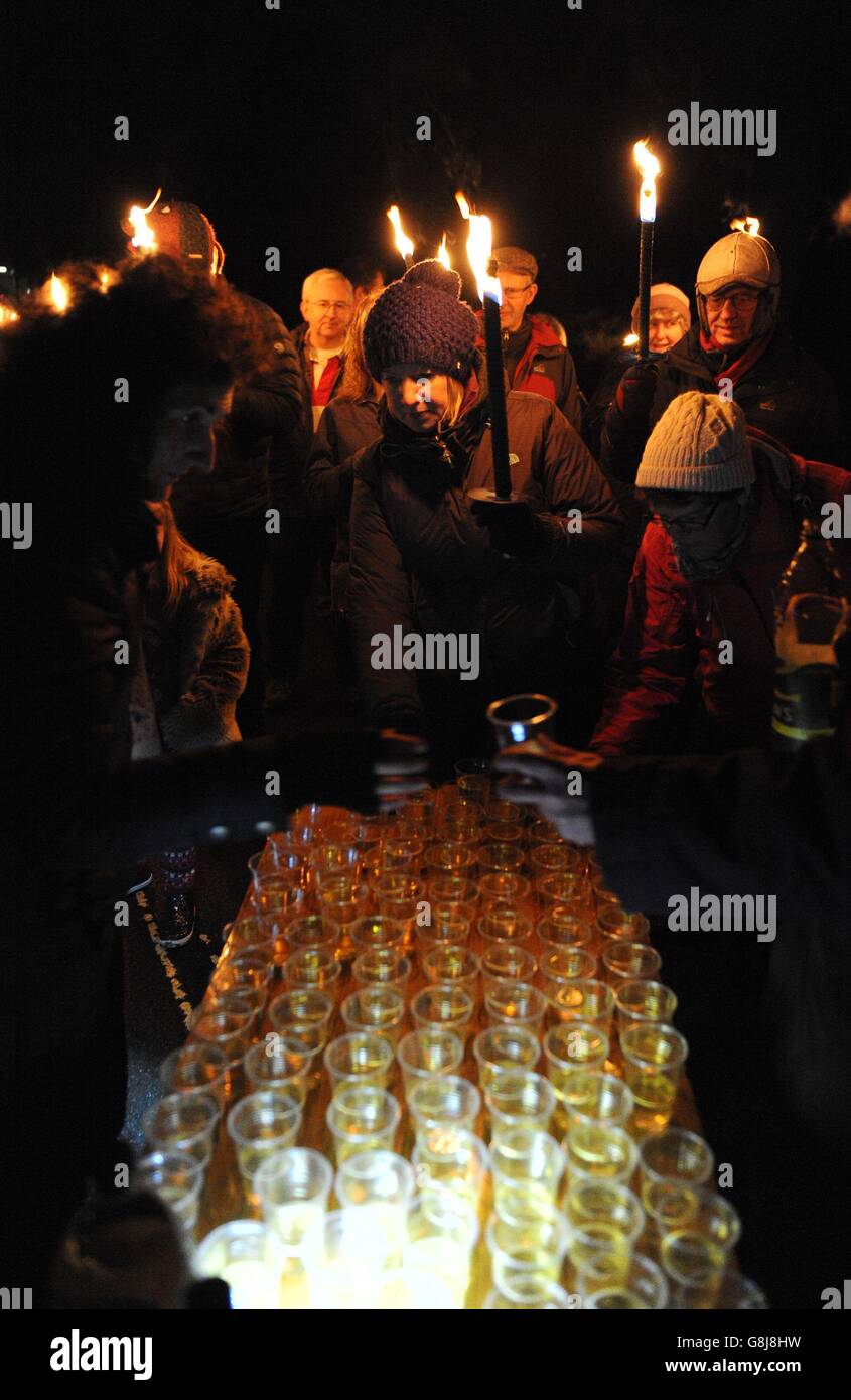 Mitglieder der Öffentlichkeit erhalten ein Glas Apfelwein, während sie sich im Vaughan Millennium Apfelgarten während einer "Wassail" in Hartley Wintney, Hampshire, versammeln. Stockfoto