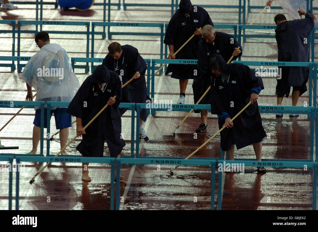 Leichtathletik - IAAF Leichtathletik-Weltmeisterschaften - Helsinki 2005 - Olympiastadion. Volenteers fegen das überschüssige Wasser auf der Strecke weg Stockfoto