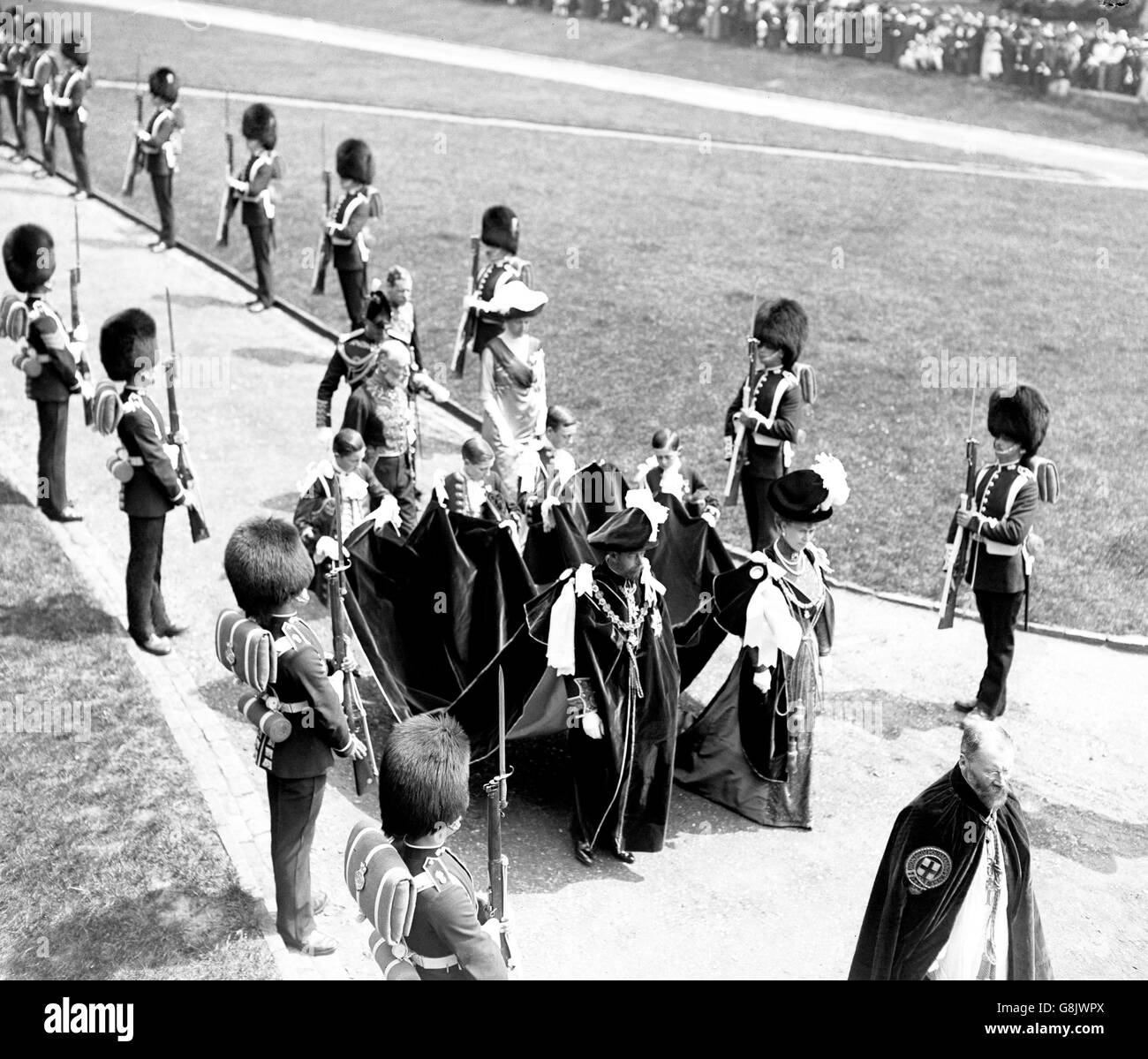 König George V und Königin Mary kleideten sich in Roben bei einer Kleiderzeremonie in Windsor. Sie gehen die Stufen hinauf, um die St. George's Chapel zu betreten. Stockfoto