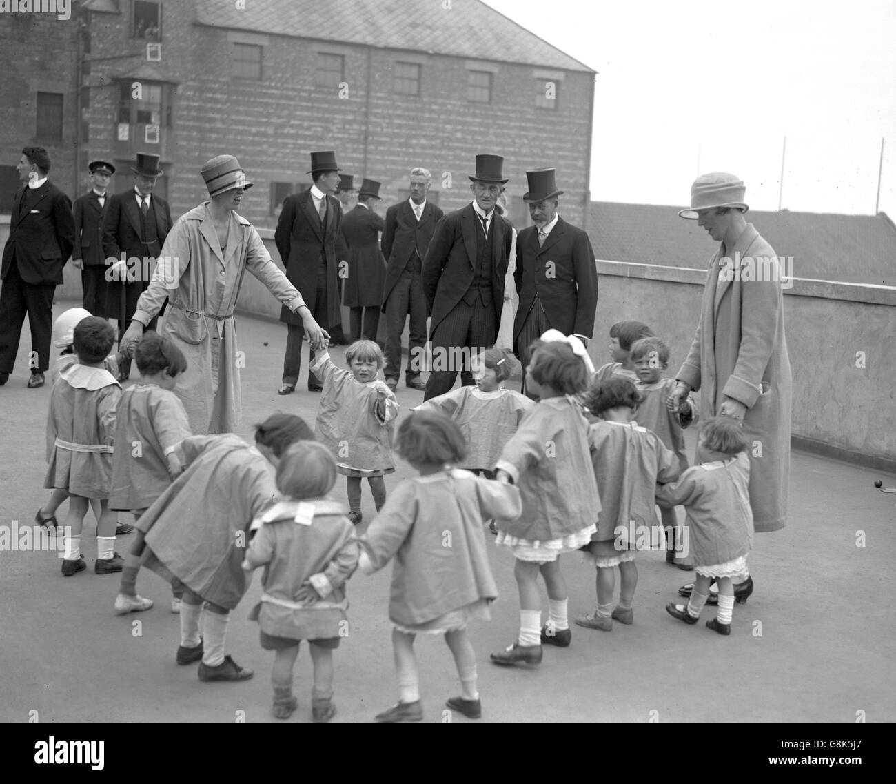 König George V beobachtet Kinder beim Spielen in der Siedlung des New College in der Pleasance während seines Besuchs in Edinburgh. Stockfoto