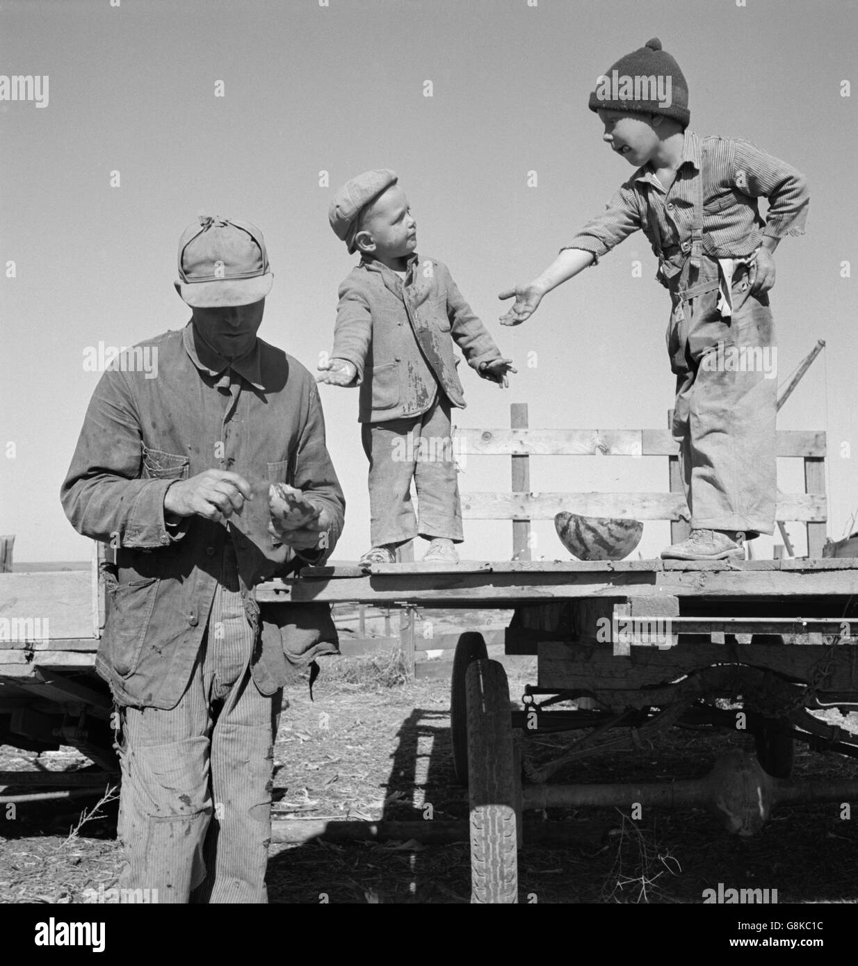 Wanderarbeitnehmer geben seine zwei Söhne Wassermelone, Tote Ochsen flach, Malheur Grafschaft, Oregon, USA, Dorothea Lange für Farm Security Administration, Oktober 1939 Stockfoto