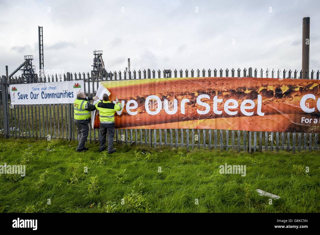 Sicherheitspersonal nimmt ein Banner "Save our Steel" ab, das von Arbeitern am Zaun vor dem Tata-Stahlwerk auf dem Hafenweg, Port Talbot, aufgestellt wurde, da die Stahlindustrie einen weiteren großen Schlag erlitten hat, nachdem Tata bestätigt hat, dass mehr als 1,000 Arbeitsplätze abgebaut werden sollen. Stockfoto