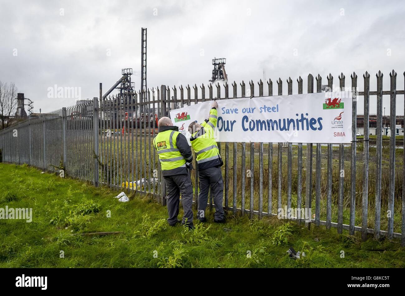 Sicherheitspersonal nimmt ein gewerkschaftliches Banner auf dem Zaun vor dem Stahlwerk Tata auf dem Hafenweg, Port Talbot, ab, da die Stahlindustrie einen weiteren großen Schlag erlitten hat, nachdem Tata bestätigt hat, dass mehr als 1,000 Arbeitsplätze abgebaut werden sollen. Stockfoto