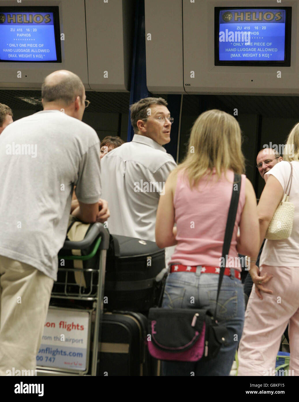 Passagiere stehen am Helios-Check-in-Schalter am Flughafen Manchester in der Warteschlange, während sie sich auf den Flug nach Paphos vorbereiten. Stockfoto