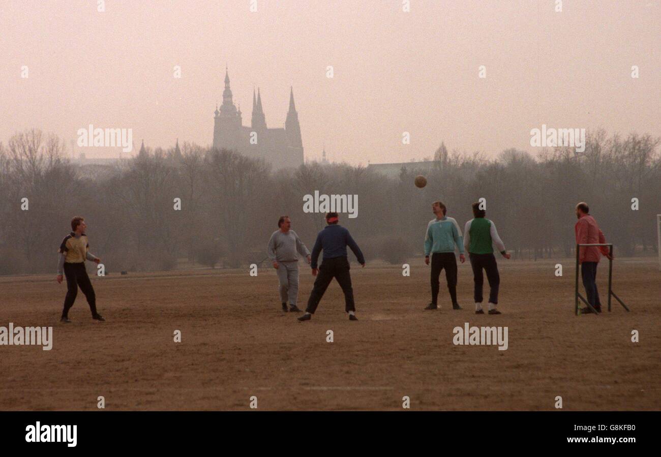 Eine Gruppe von Männern spielt Fußball mit der Prager Kathedrale Im Hintergrund Stockfoto