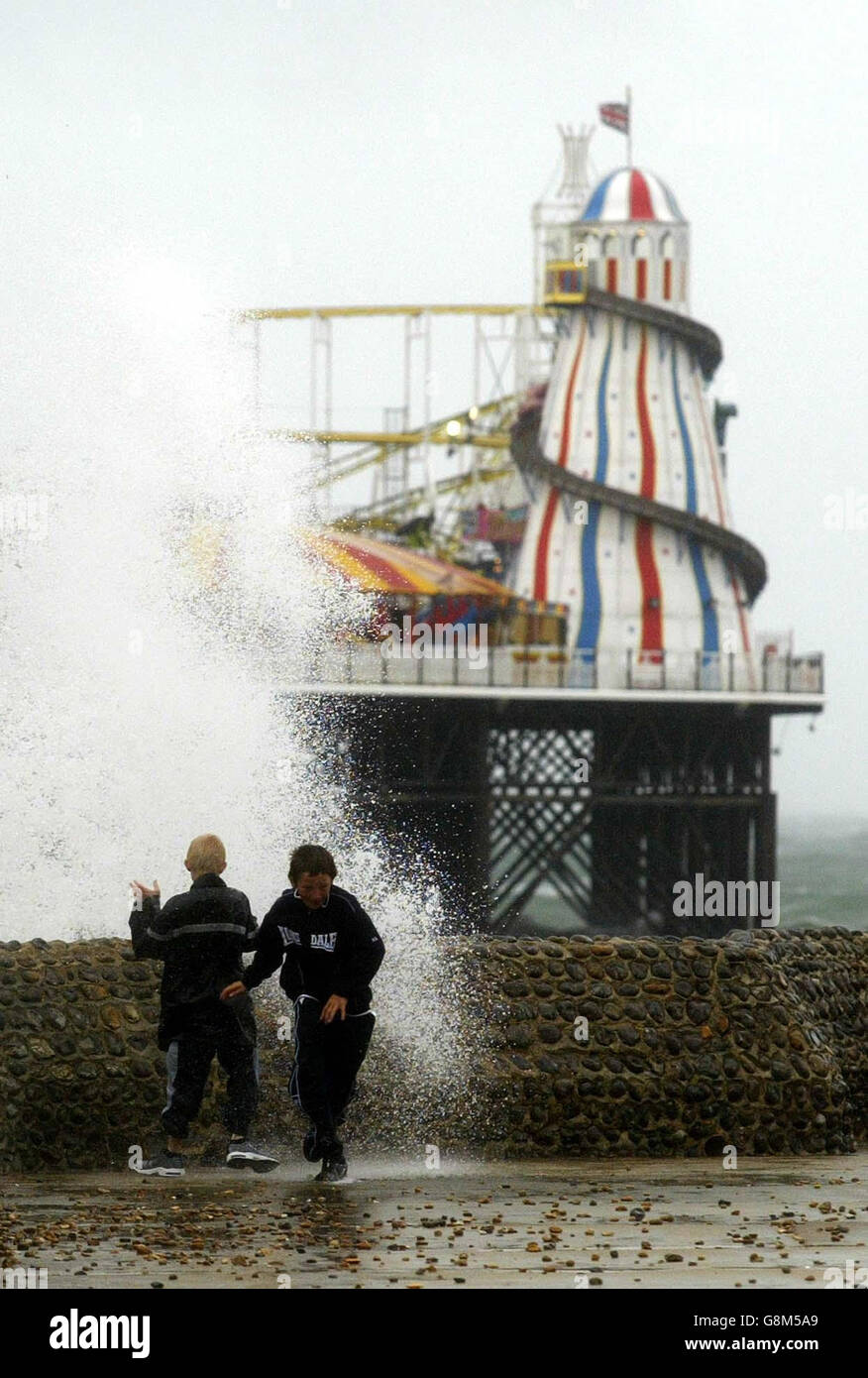 Kinder weichen bei stürmem Wetter in der Nähe des Brighton Pier, East Sussex, den Wellen aus. Stockfoto