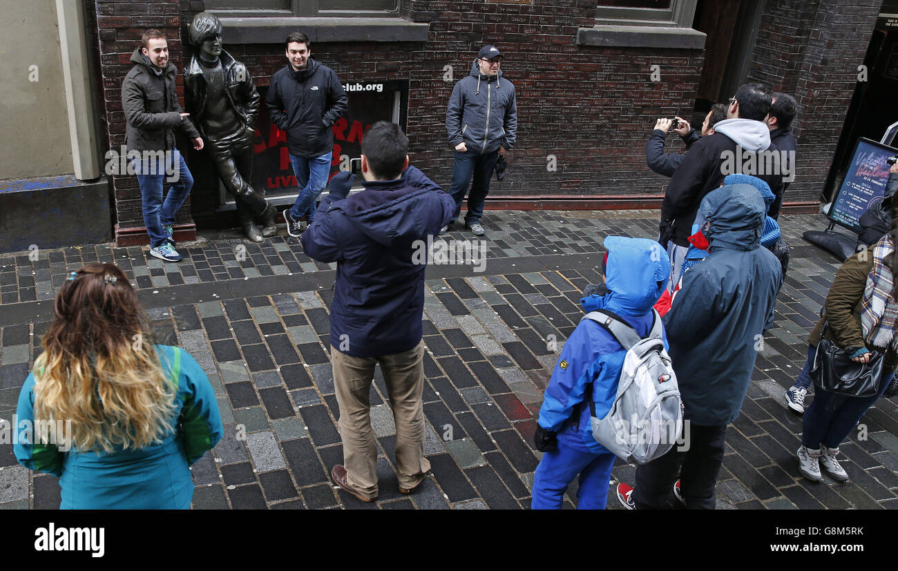 Touristen posieren für Bilder neben einer Statue von John Lennon gegenüber dem Cavern Club in der Mathew Street in Liverpool. Das Vermächtnis der Beatles fügt der Liverpool-Wirtschaft jedes Jahr 81.9 Millionen hinzu und unterstützt 2,335 Arbeitsplätze, so neue Forschungen. Stockfoto