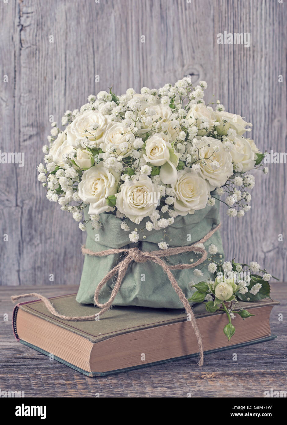 Weiße Rosen und ein Buch über hölzerne Hintergrund Stockfoto
