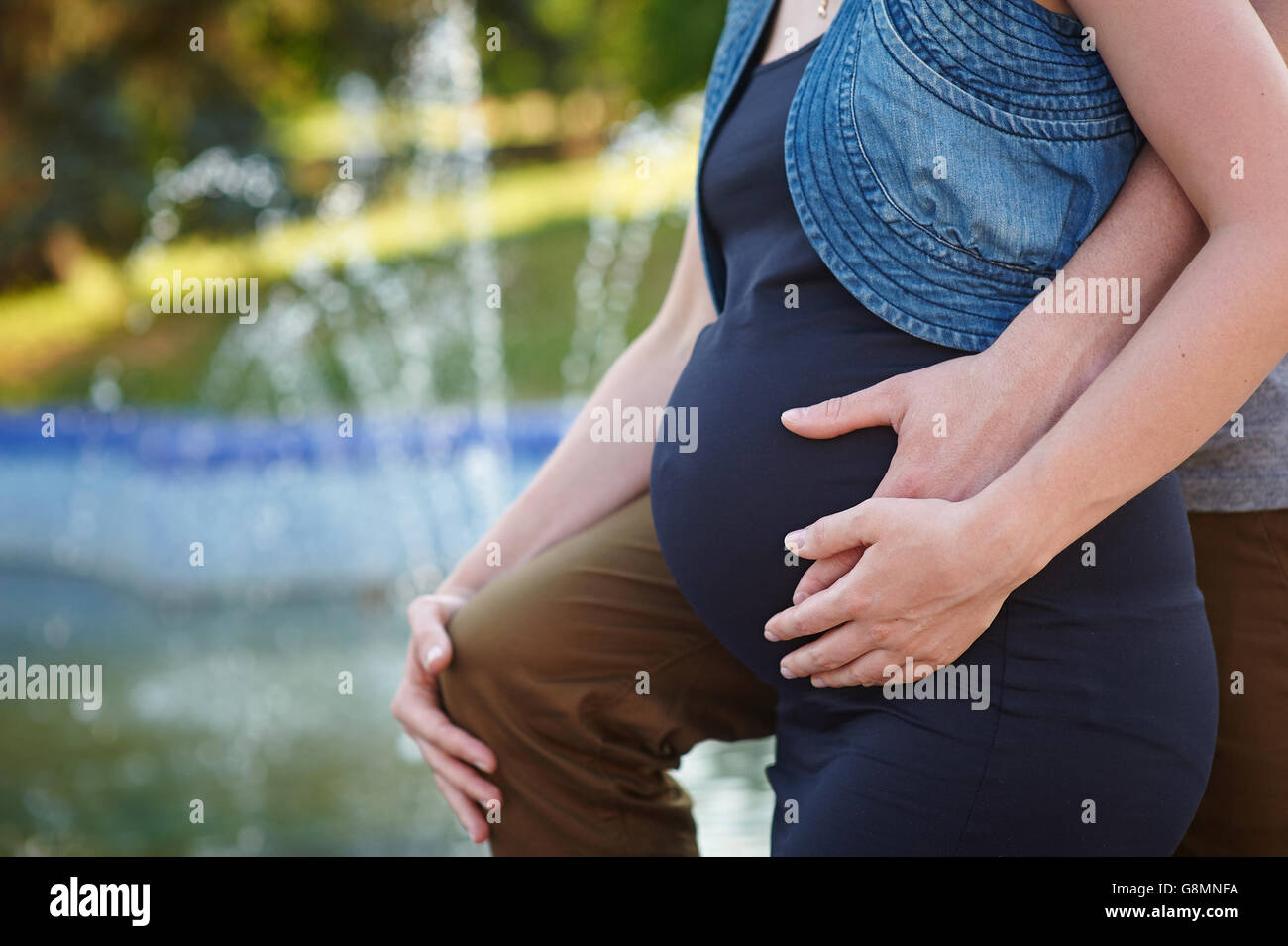 Schwangere Frau und ihr Mann halten ihre Hände auf den Bauch. Stockfoto