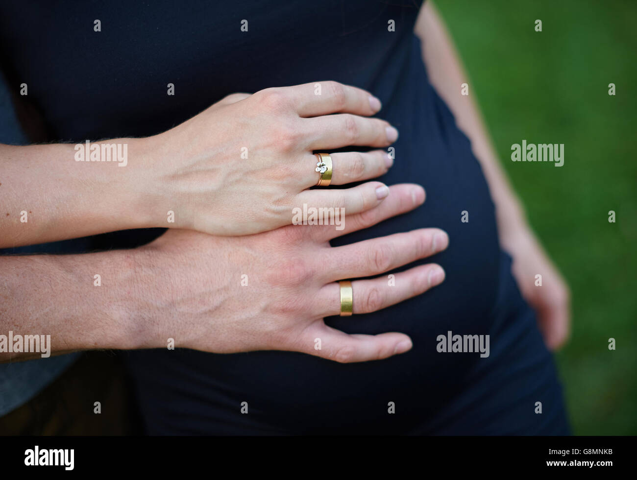 Schwangere Frau und ihr Mann halten ihre Hände auf den Bauch. Stockfoto