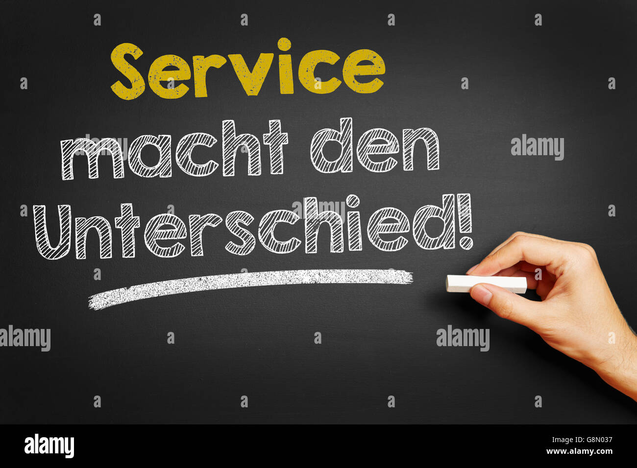 Hand, schreibt in Deutsch "Service Macht Den Unterschied!" (Service macht den Unterschied!) auf Tafel Stockfoto