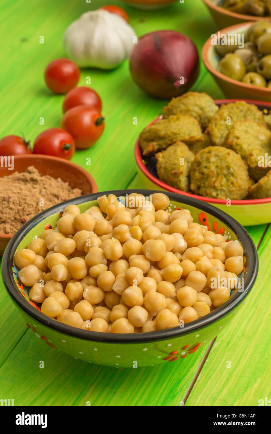 Kichererbsen, Falafel, Gewürze und Gemüse am grünen Tisch Stockfoto