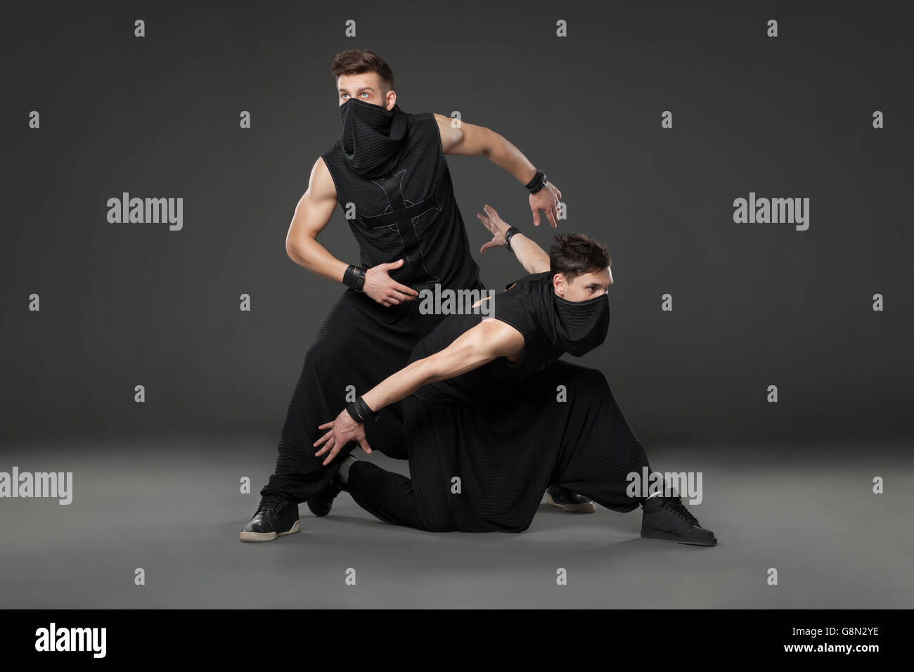 Zwei Tänzer tanzen in Ninja Kostüme vor grauem Hintergrund. Stockfoto