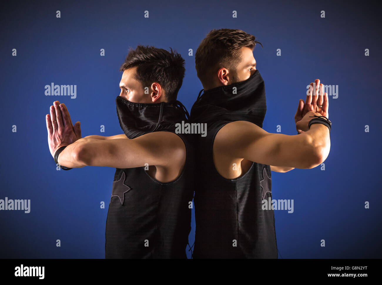 Zwei Tänzer posiert in Ninja Kostüme gegen dunkelblauen Hintergrund. Stockfoto