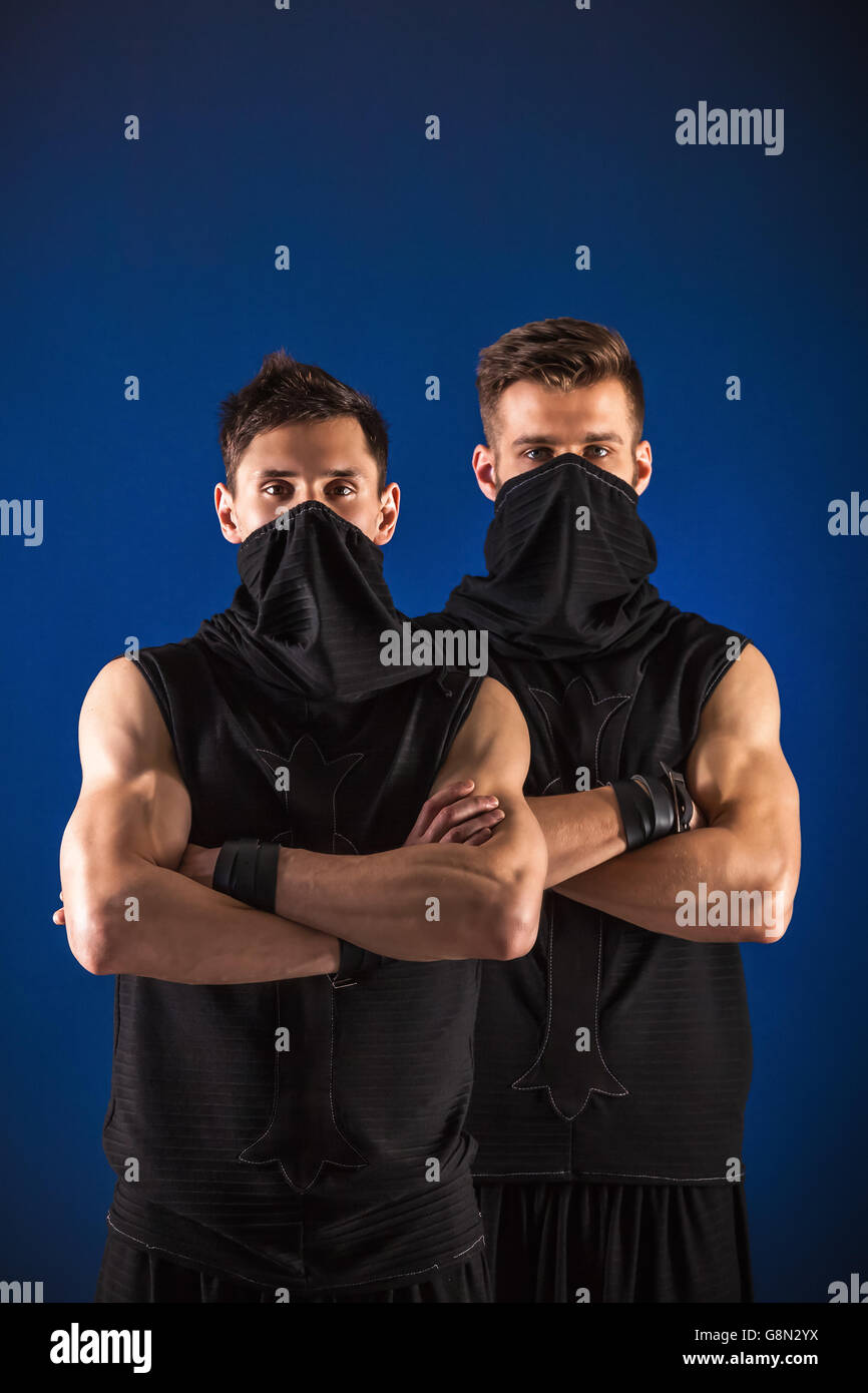 Zwei Tänzer posiert in Ninja Kostüme gegen dunkelblauen Hintergrund. Stockfoto