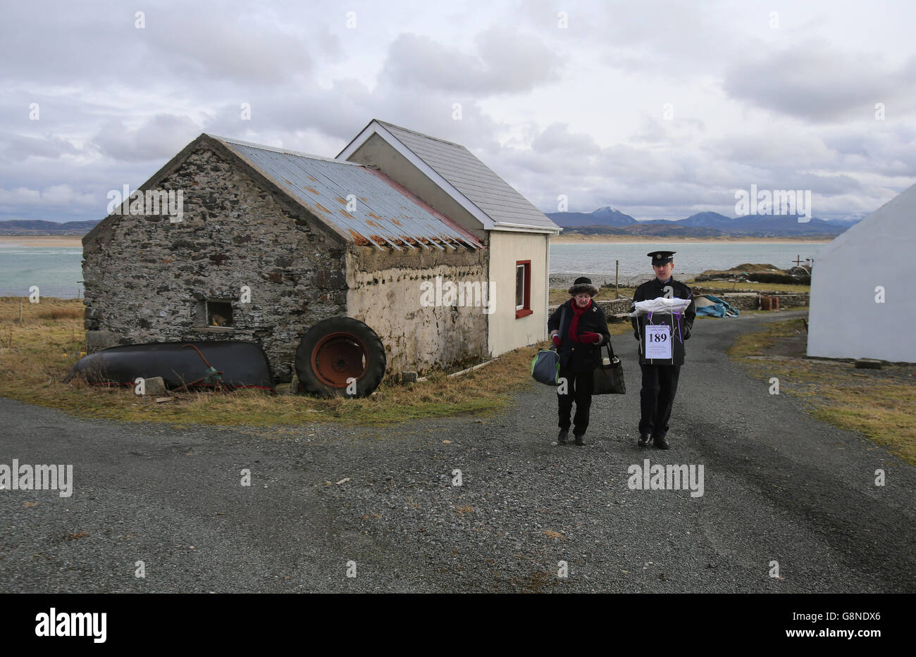 Der Vorsitzende Carmel McBride und der Garda-Sergeant Paul McGee tragen eine Wahlurne von einem Wahllokal weg, nachdem die Abstimmung auf der Insel Inishbofin abgeschlossen wurde. Die Wähler auf der abgelegenen Insel vor der Küste von Donegal gehörten zu den ersten, die bei den Parlamentswahlen in Irland, einen Tag vor dem Rest des Landes, ihre Stimme abgaben. Stockfoto