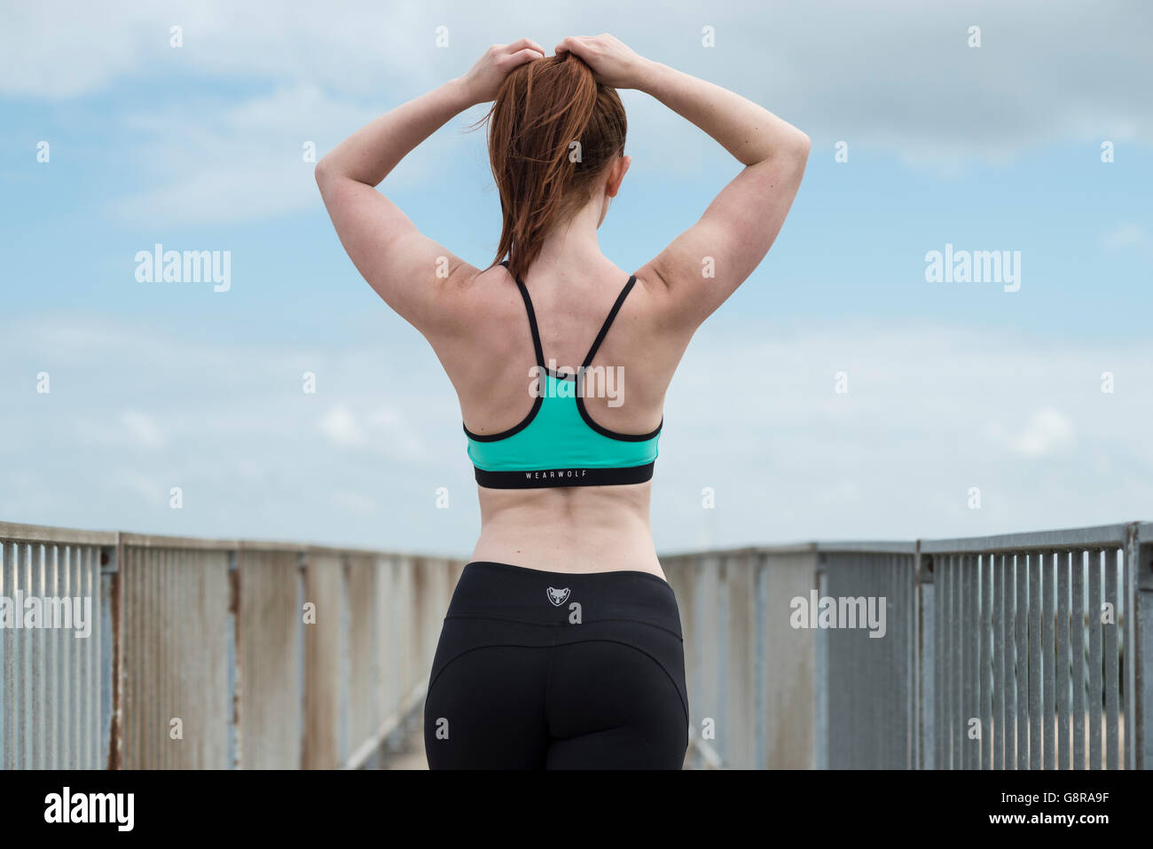 Frau trägt Fitness tragen ihr Haar einstellen von hinten betrachtet Stockfoto