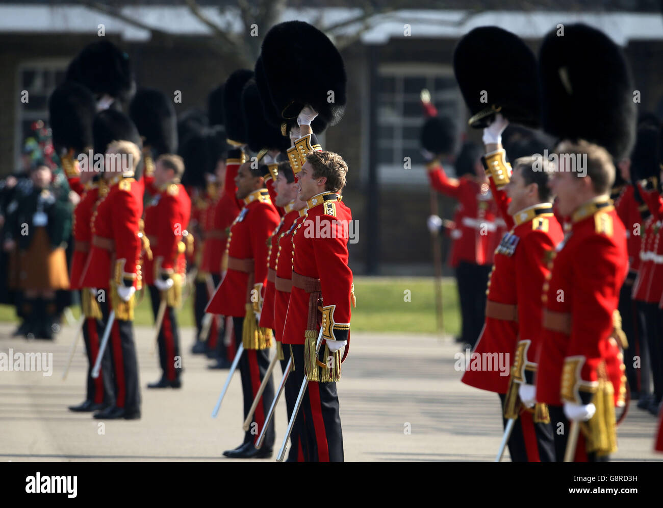 Die irischen Garden heben ihre Bärenfellmützen aus Jubel für den Herzog von Cambridge, als er die Kavallerie-Kasernen in Hounslow, West-London, zur St. Patrick's Day Parade des Regiments besucht. Stockfoto