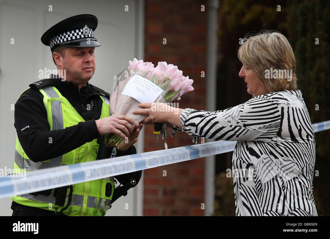 Eine Frau hinterlässt bei der Polizei ein paar Blumen in einem Haus in Dalgety Bay in Fife, wo zweijährige Zwillingsjungen ertrunken sind, nachdem sie in einen Fischteich in einem Garten in Fife gefallen sind. Stockfoto