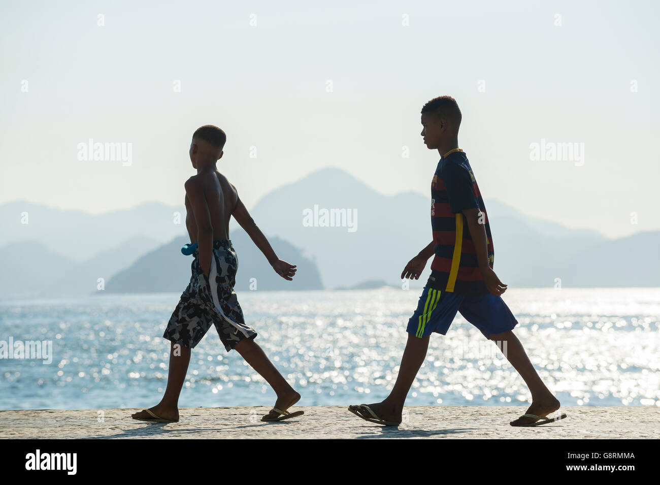 RIO DE JANEIRO - 3. April 2016: Junge Brasilianer gehen in der Silhouette auf der Promenade am Strand Copacabana an einem nebligen Morgen. Stockfoto