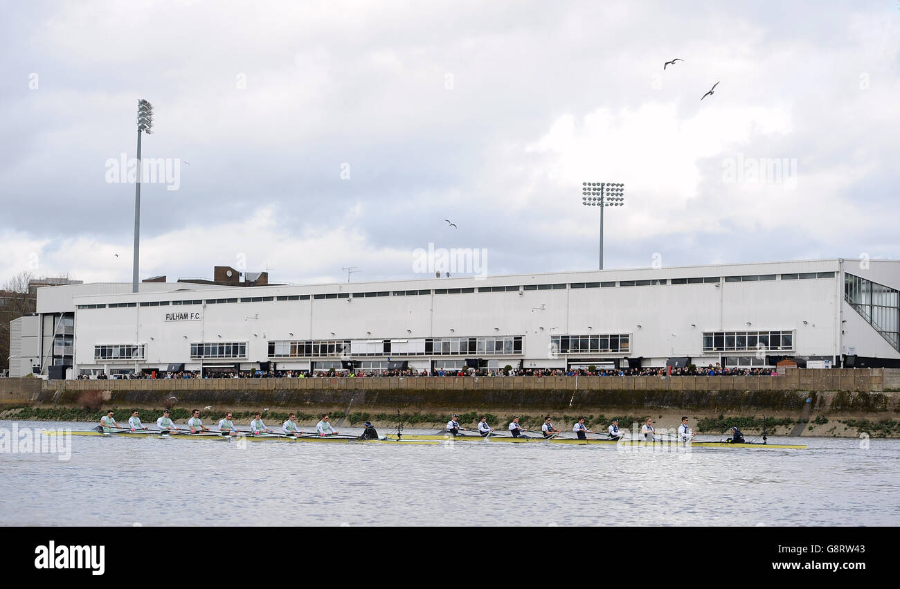 Oxford (rechts) und Cambridge Men's Blue Boat Crews passieren das Craven Cottage Stadion während des Men's Boat Race auf der Themse, London. Stockfoto