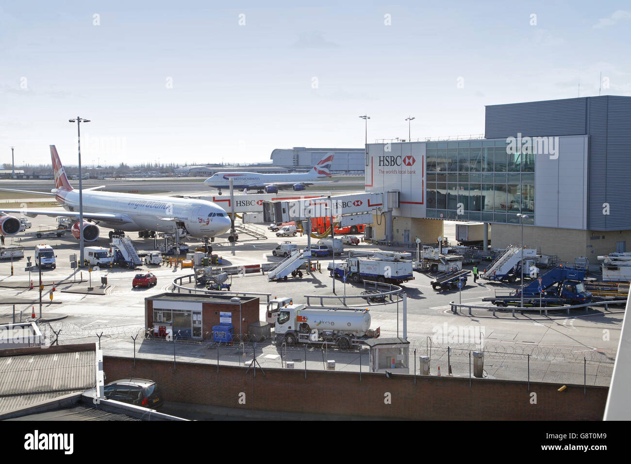 Eine Virgin Atlantic Airbus A340 ist vorbereitet und am Terminal 3 im Londoner Flughafen Heathrow geladen. BA Boeing 747 im Hintergrund Stockfoto
