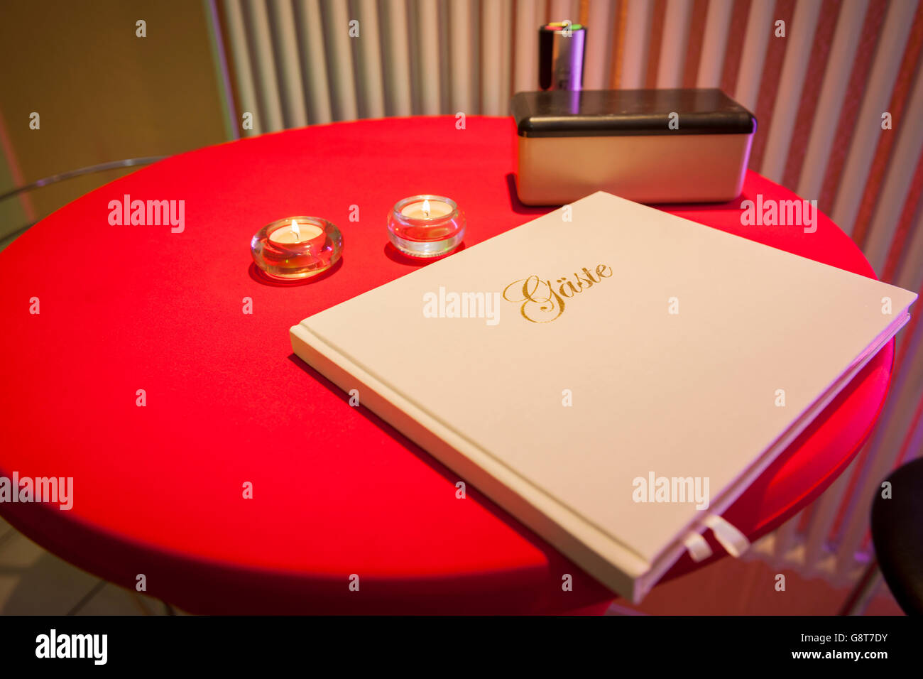 Nahaufnahme von einer roten Runde Stehstisches mit Gästebuch und Tee Licht Stockfoto