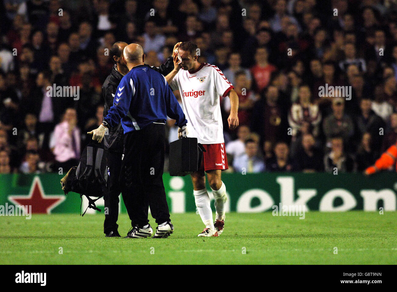 Fußball - UEFA Champions League - Gruppe B - Arsenal / FC Thun - Highbury. Alen Orman (r) von FC Thun geht nach dem Angriff von Robin van Persie, Arsenals Rotkärtchen, zur Behandlung aus Stockfoto